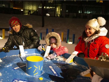 Miriam Castro, right, with her husband, Damal Radwan, and their daughter, Siwsam, participate a giant game of Tidily Winks at Nuit Blanche at the Quartier des Spectacles in Montreal on Saturday, Febr. 29, 2020.