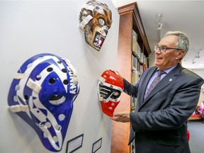 Pointe-Claire Mayor John Belvedere checks reproductions of NHL goalie masks at Stewart Hall last Friday.