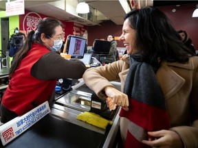Mayor Valérie Plante taps elbows with a cashier at a Chinatown shop on Thursday. Plante was there to show solidarity with the Chinese-Canadian community, which has hit hard by coronavirus fears.