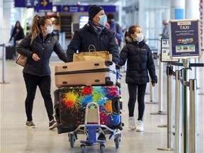 A family wearing masks walks through the domestic arrivals area at Pierre Elliott Trudeau airport in Montreal on March 16, 2020.