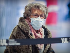 A woman wearing a mask waits for a friend to arrive at Trudeau Airport in Montreal on March 16, 2020.