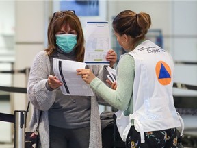 Travellers arriving at Trudeau Airport in Dorval were met by officials from the Quebec public health authority handing out flyers giving directives on the coronavirus, March 16, 2020.