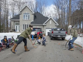 Brad Loiselle takes on the job of goalie as his wife Ashley and children take shots on him in St-Lazare, Saturday. Normally the family is at hockey games and practices with their four boys, but due to the COVID-19 restrictions in place the home driveway is being used to keep the kids busy. "Increasing numbers of people are staying at home with their families, spending time together," Lea Kabiljo writes.