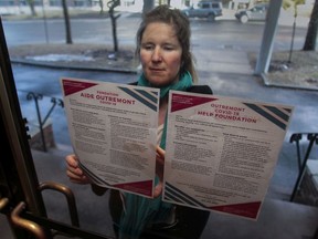 Astrid Arumae tapes up flyers on an apartment building door in the Outremont area of Montreal, Friday, March 20. An array of community support groups have sprung up in response to COVID-19, many of them on Facebook, including the Coronavirus Citizen Support Team in Outremont.