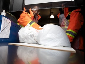 Welcome Hall Mission employee Hans St. Just slides food bags through a door outfitted with a plexiglass protective shield in Montreal, on Wednesday, March 25, 2020.