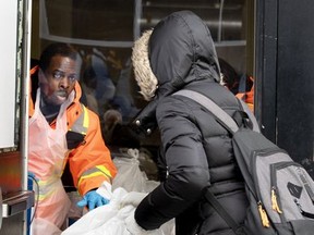 Welcome Hall Mission employee Hans St-Juste slides food bags through a door outfitted with a plexiglass protective shield in Montreal March 25, 2020.