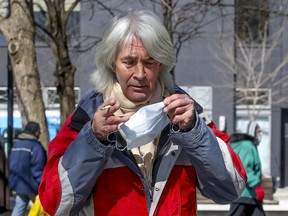 Stewart Greville puts on a mask while hanging out in Cabot Square in Montreal on Friday, March 27, 2020.