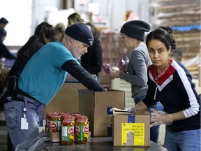 Bruce Dawe, left and Leila Ben Ammar volunteer and help pack food boxes at Moisson Montreal as the city deals with the coronavirus crisis in Montreal.