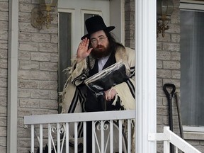 A member of the Tosh Jewish community waves to photographers before entering a home in Boisbriand March 30, 2020.  The Hasidic community was quarantined after an outbreak of COVID -19.