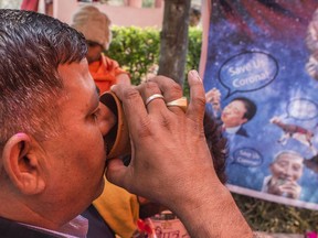 A member and supporter of the Hindu organisation 'Akhil Bharat Hindu Mahasabha' drinks cow urine, touted as a potential cure for the new coronavirus, as he attends a 'gaumutra (cow urine) party' to fight against the spread of the COVID-19 coronavirus, organised by the Akhil Bharat Hindu Mahasabha's president Chakrapani Maharaj on March 14, 2020 in New Delhi, India. In some other countries, people are turning to other dubious measures, like blowing hot air up their nostrils.