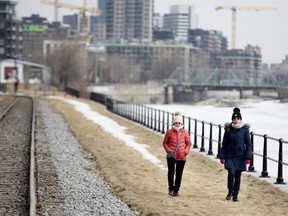 Two women walk together, at a distance, along the Lachine Canal in Montreal, on Thursday, March 19, 2020.
