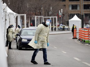 A health care worker peeks around the corner of his screening tent at the COVID-19 testing area as the city deals with the coronavirus crisis in Montreal, on Thursday, March 26, 2020.
