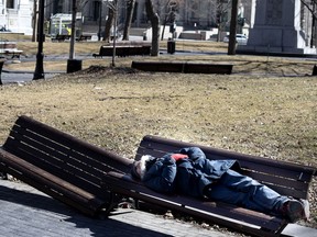 A homeless man sleeps on a bench in Dorchester Square as Montreal deals with the coronavirus crisis March 27, 2020.