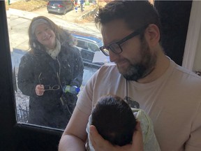 Lynda Schneider Granatstein takes a peek through a window at her newborn grandson Maximilian Batalion, held by father Eli Batalion, in Westmount March 31, 2020. Mom Tamara Granatstein took the photo.