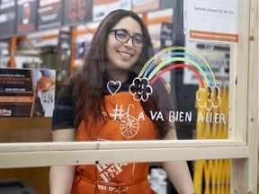 Maroua of the St. Henri Home Depot works behind a plexiglass barrier decorated with a Ca Va Aller rainbow as the city deals with the coronavirus pandemic in Montreal, on Friday, March 27, 2020. Maroura said almost all the clients have been understanding and cooperative with the new restrictions that have been put in place.