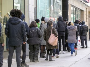 Customers leave some space among themselves while waiting to get into the SQDC store on Ste- Catherine St.