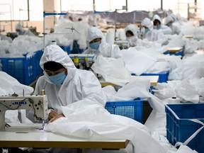 This photo taken on Feb. 28, 2020, shows workers sewing at factory making hazardous material suits to be used in the COVID-19 coronavirus outbreak, at the Zhejiang Ugly Duck Industry garment factory in Wenzhou. The coronavirus outbreak in China is preventing clothing manufacturer Ugly Duck Industry from resuming its normal production of winter coats, so it has pivoted to another in-demand product: hazmat suits.