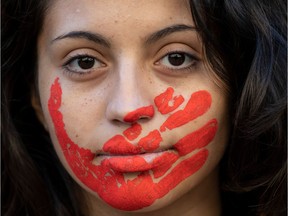 A woman with a handprint painted over her mouth poses for a picture before taking part in a march on International Women's Day in Santiago, on March 8, 2020. - Protests, strikes and studies -- people around the globe are taking action to mark International Women's Day and to push for action to to obtain equality.