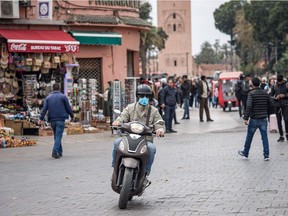 A man wearing a protective mask rides his scooter at Marrakesh's Jamaa el-Fna square in Morocco on March 16, 2020.