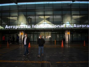 Two men wearing face masks as a preventive measure against the spread of the new coronavirus, COVID-19, leave Guatemala City's La Aurora International Airport which remains closed on March 17, 2020.