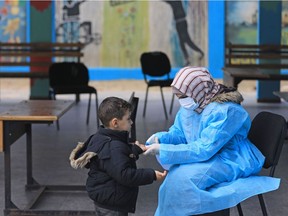 A Palestinian health worker wearing a protective facemask checks the body temperature of a child at a United Nations Relief and Works Agency for Palestinian Refugees (UNRWA) school at al-Shati refugee camp in Gaza City on March 18, 2020, as preparations were underway to receive, examine and isolate  victims of the Covid-19 coronavirus.