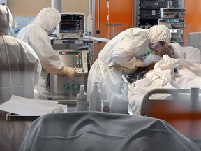 A medical worker in protective gear (R) tends to a patient on March 24, 2020 at the new COVID 3 level intensive care unit for coronavirus COVID-19 cases at the Casal Palocco hospital near Rome, during the country's lockdown aimed at stopping the spread of the COVID-19 (new coronavirus) pandemic. (Photo by Alberto PIZZOLI / AFP)