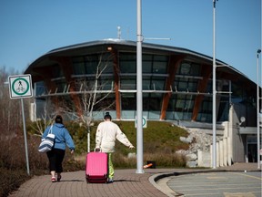 Travellers approach the Douglas-Peace Arch border crossing to return to Canada on foot, in Surrey, B.C., on Monday, March 16, 2020. Prime Minister Justin Trudeau says Canada is closing its borders to most people who are not citizens or permanent residents to slow the spread of COVID-19.