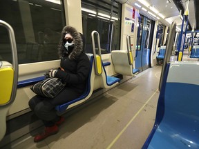 A woman wears a mask while sitting a near-empty métro car pulling out of the Angrignon station in Montreal March 16, 2020.