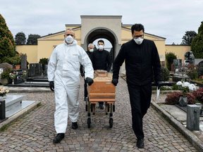 Pallbearers pull the coffin of a deceased person for a funeral ceremony into the cemetery of Grassobbio, Lombardy, Italy, on March 23, 2020, in the absence of quarantined relatives.