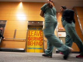 Staff members at the Jewish General Hospital walk past a sign on elevator door on March 2, 2020, instructing people to wash their hands during coronavirus pandemic.