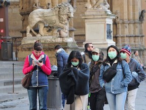 People wearing protective masks walk through Florence as Italy battles a coronavirus outbreak, in Florence, Italy, on Saturday, March 7, 2020.