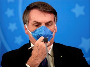 Brazil's President Jair Bolsonaro adjusts his protective face mask at a press statement during the coronavirus disease (COVID-19) outbreak in Brasilia, Brazil, March 20, 2020.