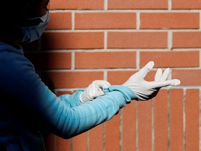 A woman wearing protective face mask and gloves waits for the food distribution organized by the Sant'Egidio Community at San Gaudenzio parish during the lockdown to prevent the spread of coronavirus disease (COVID-19), in Rome, Italy, March 23, 2020. REUTERS/File Photo