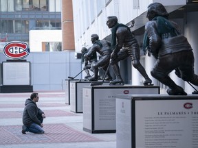 Keith Hynes reads the biography of his hero, Montreal Canadiens icon Jean Beliveau, outside the Bell Centre on March 12, 2020.