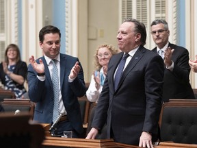 Quebec Premier Francois Legault is applauded by Quebec Minister of Immigration, Diversity and Inclusiveness Simon Jolin Barrette, left, as he stands to vote on the secularism law, Bill 21, at the National Assembly in Quebec City, Sunday, June 16, 2019.