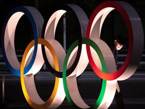 A man wearing a protective face masks, following the outbreak of the coronavirus, looks to The Olympic rings in front of the Japan Olympics Museum in Tokyo, Japan, March 3, 2020. REUTERS/Athit Perawongmetha