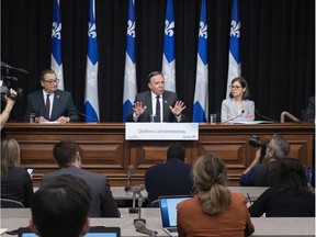 Quebec Premier Francois Legault, flanked by Quebec national public health director Horacio Arruda, left, and Quebec Health Minister Danielle McCann, responds to reporters questions at a daily news conference on the COVID-19 pandemic on March 17, 2020, at the legislature in Quebec City.