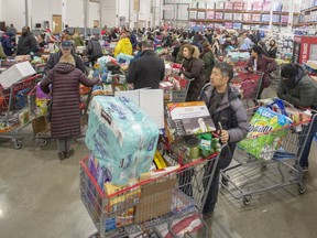 Customers lineup at the checkout area at a Costco store on March 13, 2020, in Montreal.
