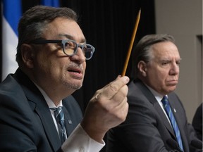Horacio Arruda, Quebec director of public health, responds to reporters during a news conference on the COVID-19 pandemic, Wednesday, March 25, 2020 at the National Assembly in Quebec City. Quebec Premier François Legault, right, looks on.