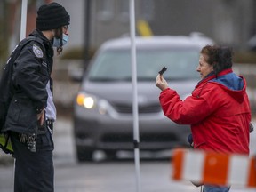 A woman shows her identification to a security guard at a barricade leading into the Tosh Jewish community in Boisbriand. The Hasidic community has been quarantined after an outbreak of COVID-19.