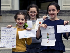 Sisters Nedivah, left, Hadar and Kinneret Finegold outside their Westmount home, with messages and envelopes they have prepared for their grandparents to read during the Passover seder, since because of COVID-19 the family will not be able to be together.