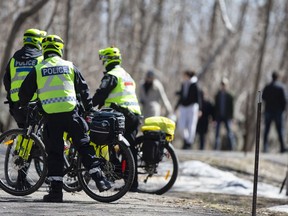 Police on bicycles monitor foot traffic on Mount Royal to ensure people keep a distance from each other by Beaver Lake in Montreal on Saturday, April 4, 2020.