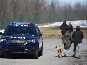 A police car drives down a path on Mount Royal to ensure people keep a distance from each other by Beaver Lake in Montreal on Saturday, April 4, 2020.