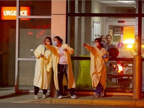 Nurses and staff point as they watch police cars, fire trucks and public works vehicles drive past with lights and horns blaring in a show of solidarity at the Anna Laberge Hospital in Châteauguay, Quebec, April 6, 2020