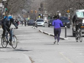 Practising social distancing, cyclists keep a good distance away from jogger near Lafontaine Park on Wednesday April 8, 2020.