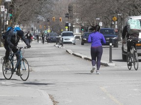Practising social distancing, cyclists keep a good distance as they move around a jogger near La Fontaine Park in Montreal on Wednesday April 8, 2020.