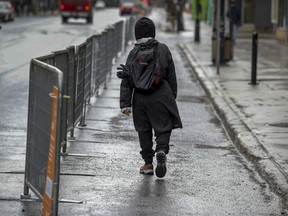 A pedestrian walks on the protected part of Mount-Royal Ave. in Montreal Monday April 13, 2020.  The city put up barricades to create a safe corridor to allow people to allow proper space when walking on the street. (John Mahoney / MONTREAL GAZETTE) ORG XMIT: 64253 - 5188