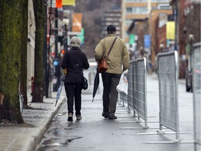 Pedestrians walk on the protected part of Mount-Royal Ave. April 13, 2020. The city put up barricades to create a safe corridor to allow people proper space for physical distancing when walking on the street.
