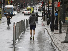 A man runs on the protected part of Mount-Royal Ave. in Montreal Monday April 13, 2020.  The city put up barricades to create a safe corridor to allow people to allow proper space when walking on the street.