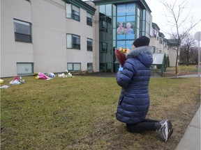 Mary prays before leaving flowers at Residence Herron in Dorval, west of Montreal Monday April 13, 2020.  Mary's mother had been a resident of the long term care facility where more than 30 people have died since March.